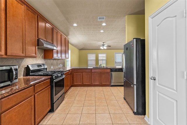 kitchen featuring stainless steel appliances, light tile patterned floors, decorative backsplash, dark stone countertops, and ceiling fan