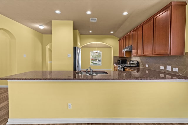 kitchen featuring stainless steel appliances, light hardwood / wood-style floors, sink, kitchen peninsula, and decorative backsplash