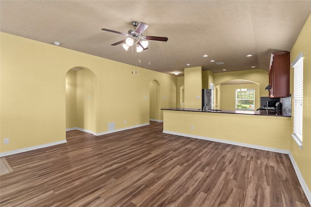 unfurnished living room with dark hardwood / wood-style floors and ceiling fan with notable chandelier