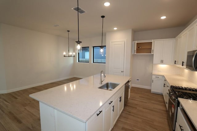 kitchen with white cabinetry, sink, stainless steel appliances, and an island with sink