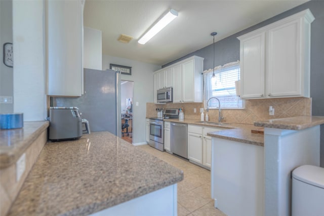 kitchen featuring white cabinetry, sink, stainless steel appliances, tasteful backsplash, and decorative light fixtures