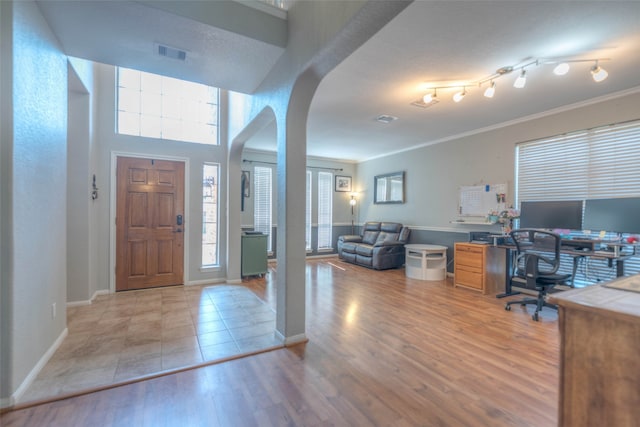 entrance foyer with crown molding and light hardwood / wood-style floors