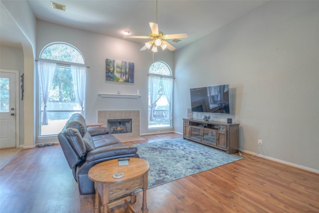 living room featuring ceiling fan, plenty of natural light, wood-type flooring, and a fireplace