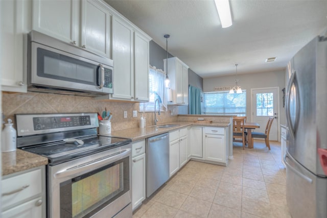 kitchen with white cabinets, sink, decorative light fixtures, kitchen peninsula, and stainless steel appliances