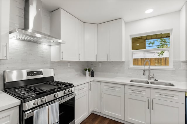 kitchen featuring dark hardwood / wood-style floors, white cabinets, wall chimney exhaust hood, sink, and stainless steel gas range oven