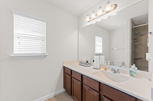 bathroom with a tile shower, tile patterned floors, vanity, and toilet