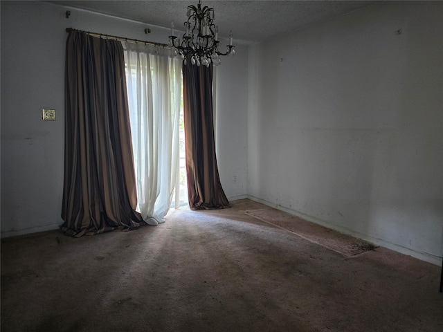 unfurnished room with a textured ceiling, a notable chandelier, and carpet