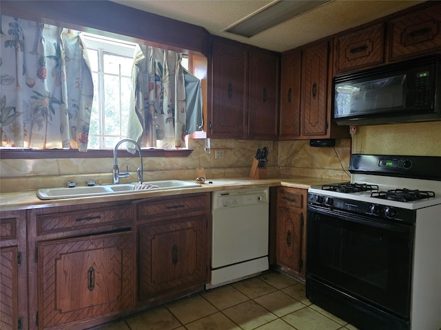 kitchen with light tile patterned flooring, black appliances, sink, and backsplash