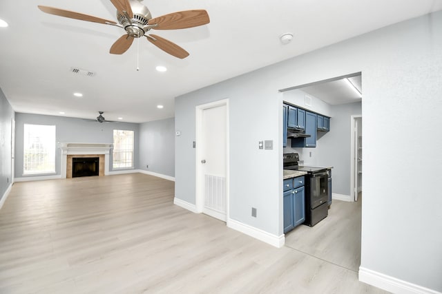 kitchen with light wood-type flooring, ceiling fan, a tiled fireplace, black / electric stove, and blue cabinets