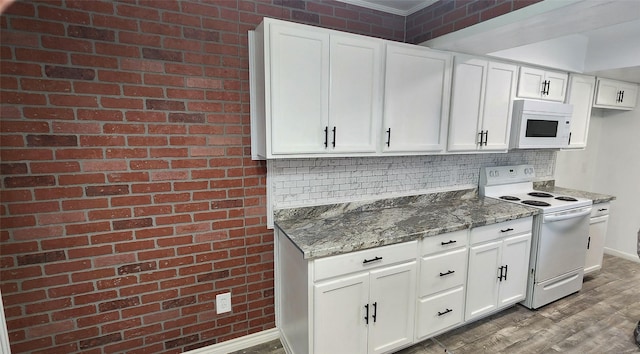 kitchen featuring white appliances, hardwood / wood-style flooring, white cabinetry, and dark stone countertops