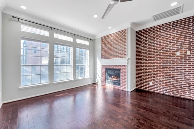 unfurnished living room featuring dark wood-type flooring, a brick fireplace, ceiling fan, ornamental molding, and brick wall