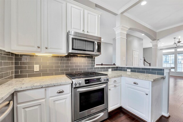 kitchen featuring ornate columns, dark wood-type flooring, stainless steel appliances, crown molding, and white cabinets