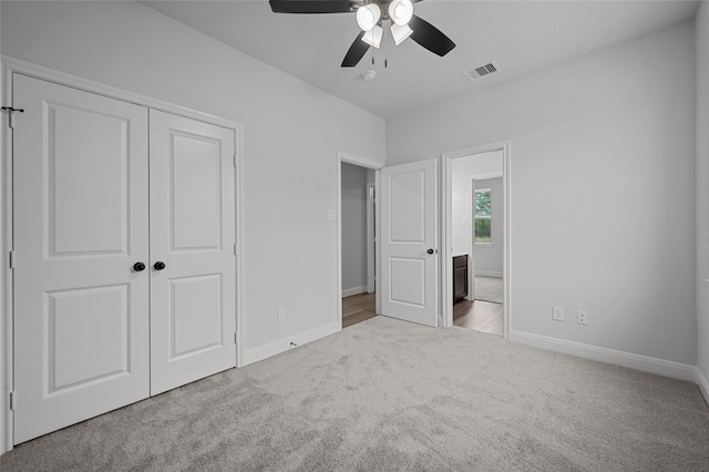 unfurnished bedroom featuring ceiling fan, a closet, and light carpet