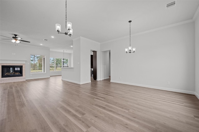 unfurnished living room featuring ceiling fan with notable chandelier, a fireplace, light wood-type flooring, and crown molding