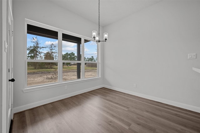 unfurnished dining area featuring wood-type flooring and an inviting chandelier