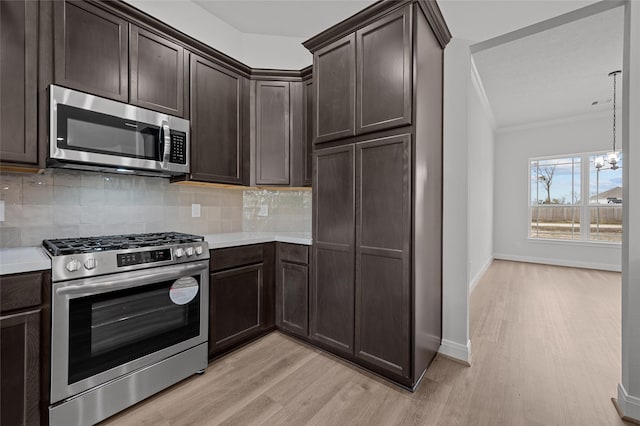 kitchen with backsplash, stainless steel appliances, a notable chandelier, and crown molding