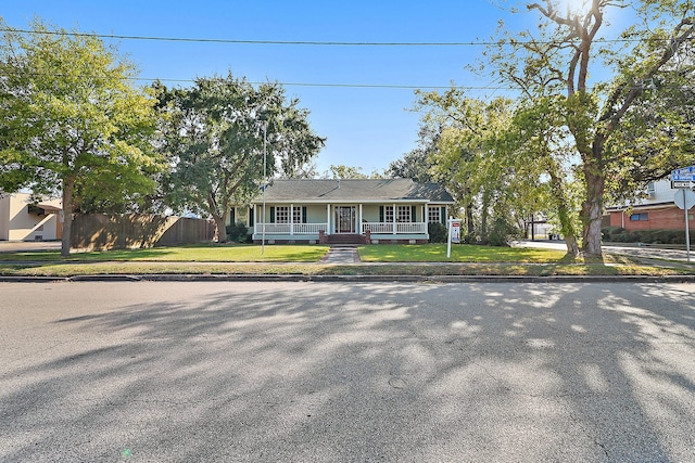 ranch-style home featuring covered porch and a front yard