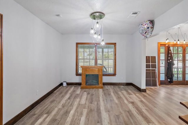 unfurnished dining area featuring a textured ceiling and light hardwood / wood-style floors