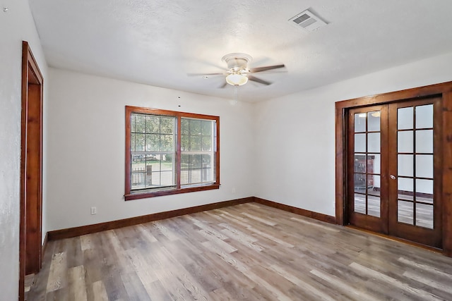 spare room with light hardwood / wood-style flooring, french doors, a textured ceiling, and ceiling fan