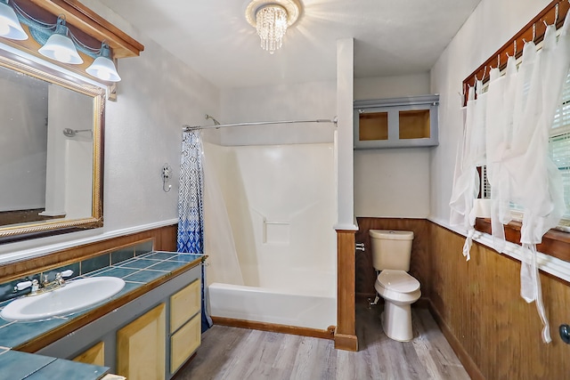 full bathroom with toilet, shower / bath combination with curtain, wood-type flooring, vanity, and wood walls