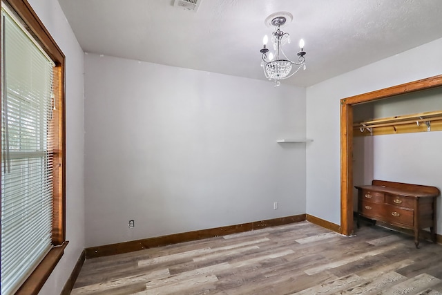 unfurnished bedroom featuring a closet, a notable chandelier, and hardwood / wood-style flooring