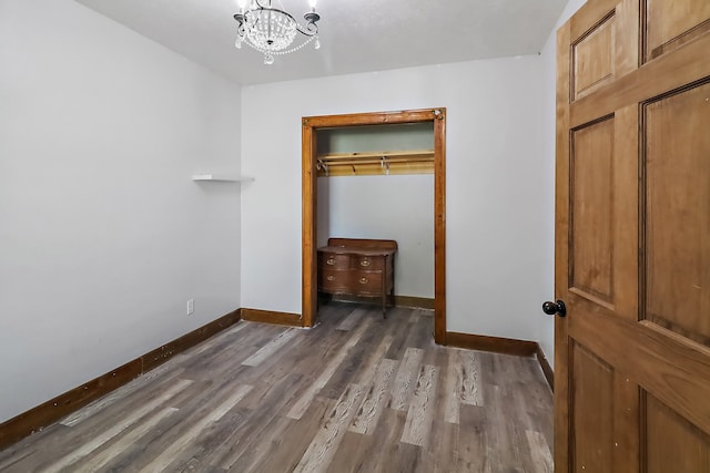 unfurnished bedroom featuring a chandelier, a closet, and dark hardwood / wood-style flooring