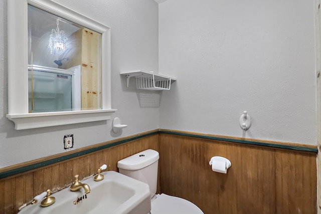 bathroom with toilet, an enclosed shower, sink, and wooden walls