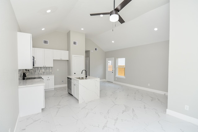 kitchen with sink, white cabinetry, backsplash, stainless steel appliances, and a center island with sink