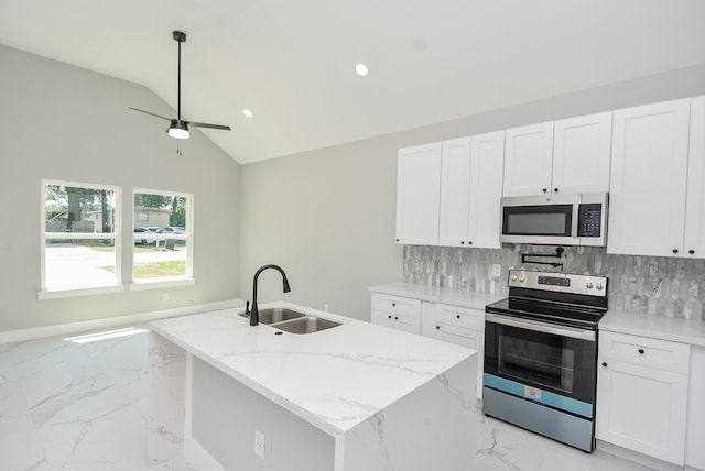 kitchen with light stone counters, white cabinets, sink, a center island with sink, and appliances with stainless steel finishes