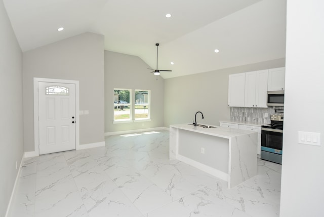 kitchen with vaulted ceiling, white cabinetry, decorative backsplash, stainless steel appliances, and a center island with sink