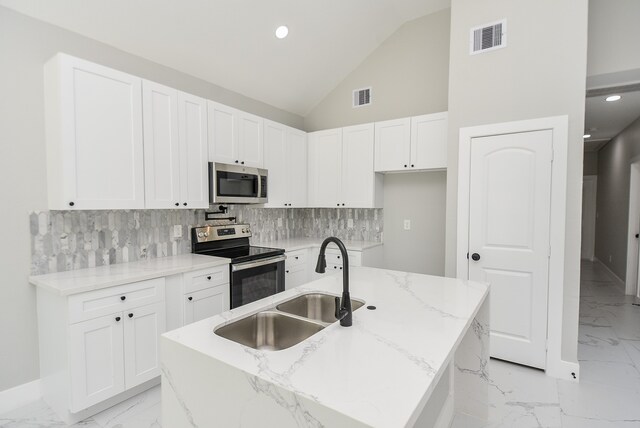 kitchen with stainless steel appliances, an island with sink, light stone countertops, and sink