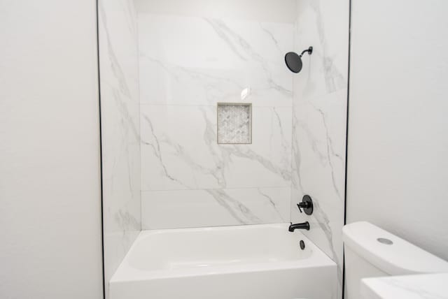 bathroom featuring tiled shower / bath combo and toilet