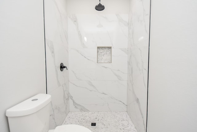 bathroom featuring tiled shower and toilet