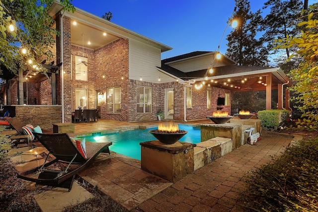 view of pool featuring ceiling fan, a fire pit, and a patio area