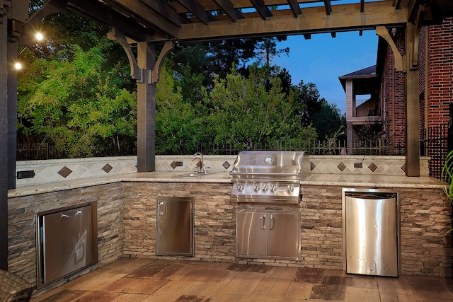 patio terrace at dusk with an outdoor kitchen, sink, and grilling area