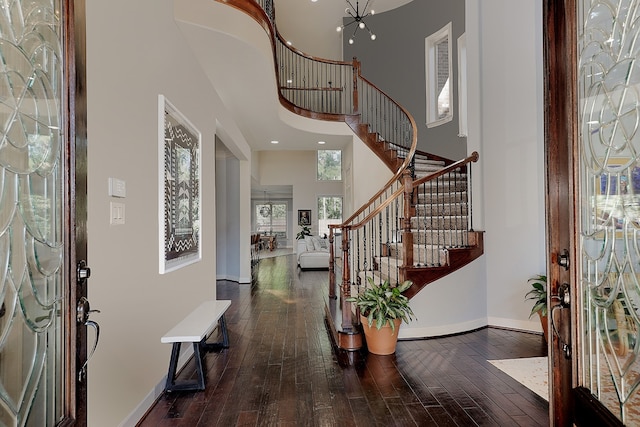 entrance foyer with a towering ceiling, dark hardwood / wood-style floors, and a chandelier