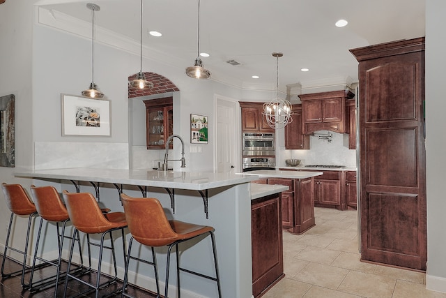 kitchen with pendant lighting, a breakfast bar, sink, decorative backsplash, and ornamental molding