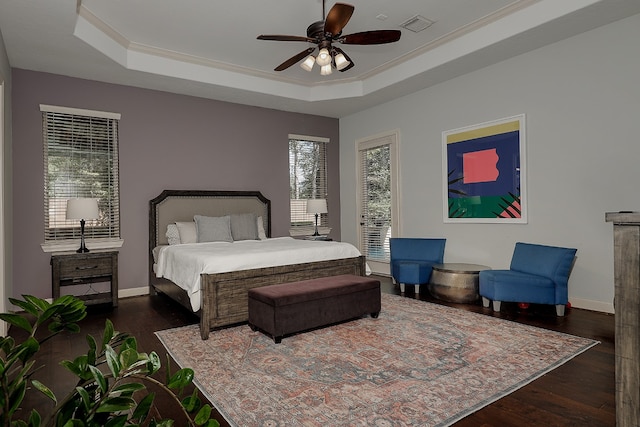 bedroom featuring a raised ceiling, dark hardwood / wood-style floors, ornamental molding, and ceiling fan