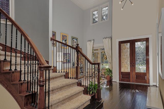 foyer entrance with a towering ceiling, a healthy amount of sunlight, dark wood-type flooring, and french doors