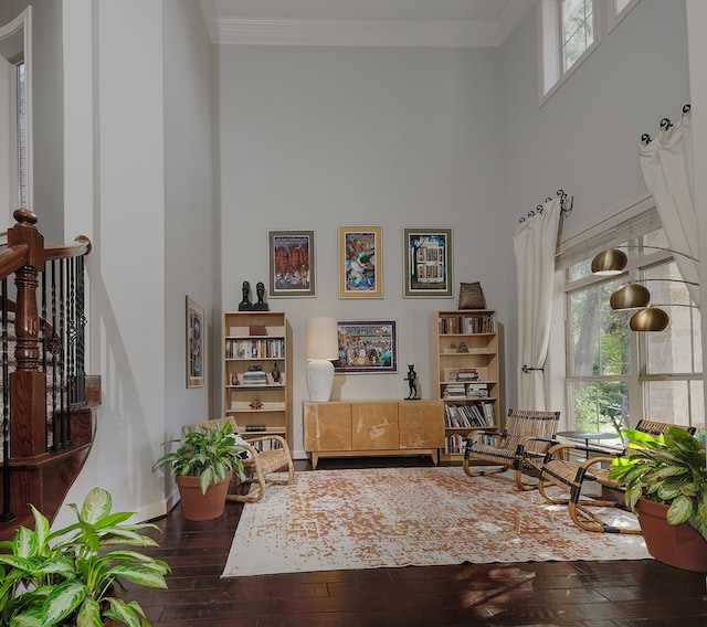 sitting room with a towering ceiling, ornamental molding, and hardwood / wood-style floors