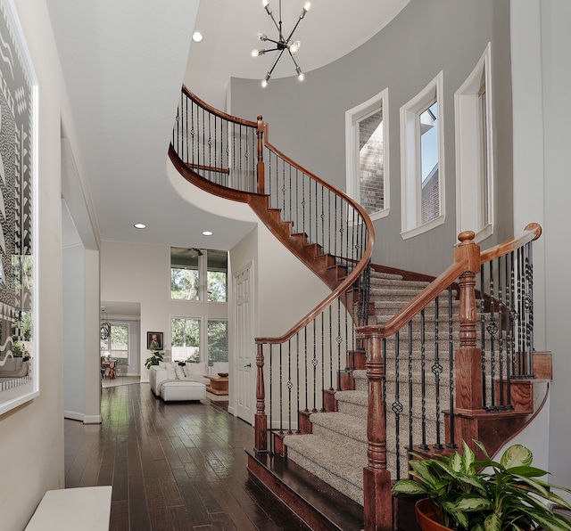 entryway with an inviting chandelier, dark hardwood / wood-style floors, and a high ceiling