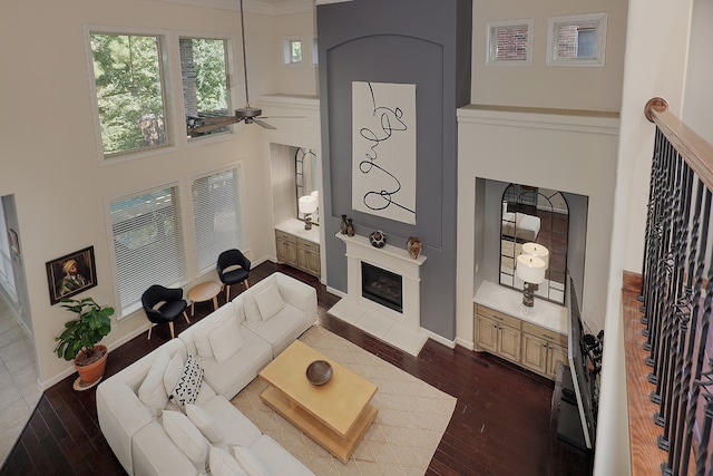 living room with a towering ceiling, dark hardwood / wood-style flooring, and ceiling fan