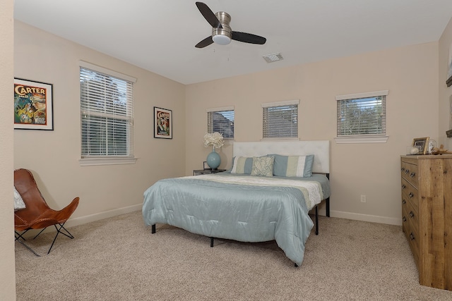 carpeted bedroom featuring multiple windows and ceiling fan