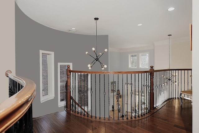 hall with hardwood / wood-style flooring, crown molding, and a chandelier