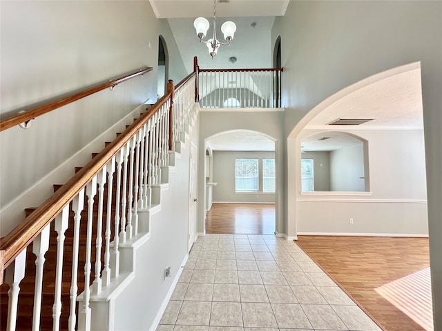 foyer entrance featuring high vaulted ceiling, an inviting chandelier, and light hardwood / wood-style floors