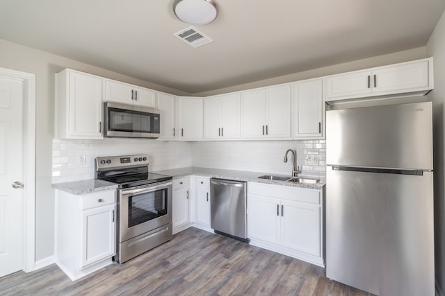 kitchen with sink, white cabinetry, appliances with stainless steel finishes, dark hardwood / wood-style flooring, and decorative backsplash