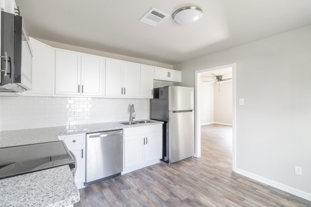 kitchen featuring light wood-type flooring, sink, stainless steel appliances, backsplash, and white cabinets