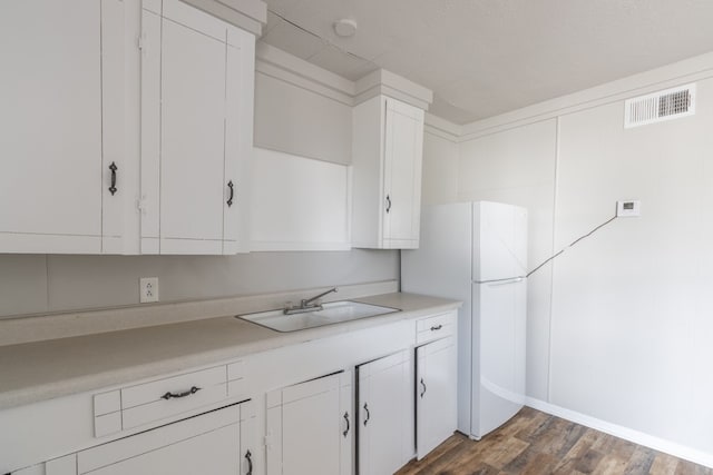 kitchen with white fridge, white cabinetry, sink, and dark hardwood / wood-style floors