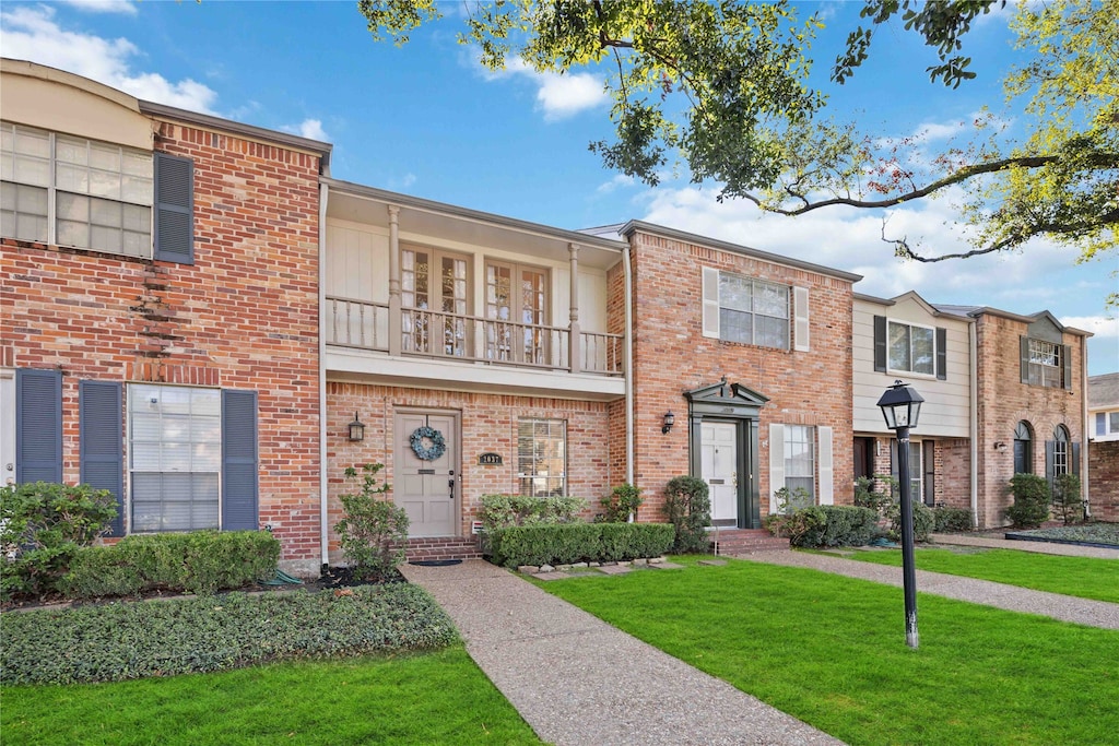 townhome / multi-family property with a front yard and a balcony