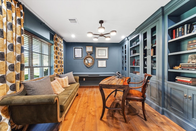 office with built in shelves, hardwood / wood-style floors, and an inviting chandelier